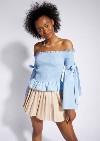 model in blue smocked top with long bell sleeve with bow details