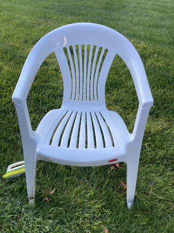 Plastic outdoor seat  connected  grass, with striped backrest and seat. A tiny  reddish  tag is disposable   connected  the beforehand   edge