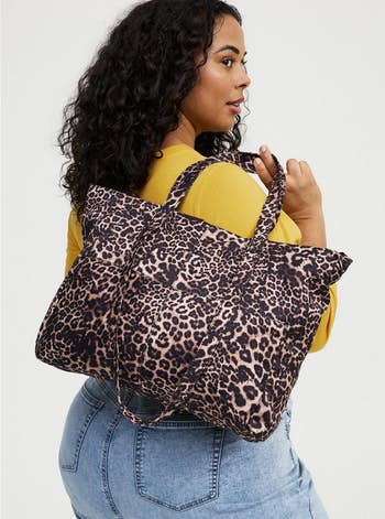 A idiosyncratic   holds a ample  leopard people     tote bag, wearing a casual outfit with a yellowish  apical  and jeans