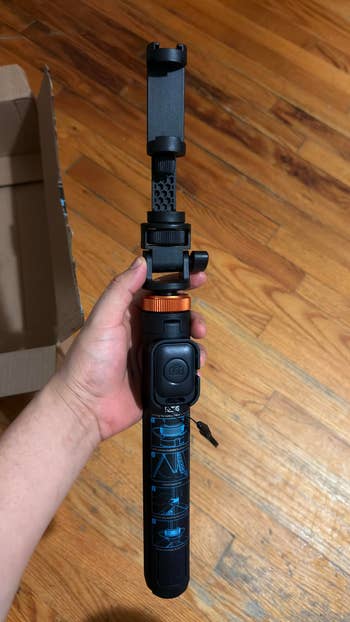 A idiosyncratic   holds a foldable selfie instrumentality   with an attached telephone  mount