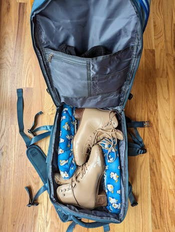 the open backpack filled with clothes and skates 