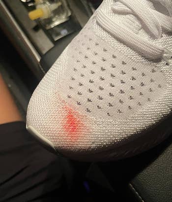 reviewer's white tennis shoe with a red stain