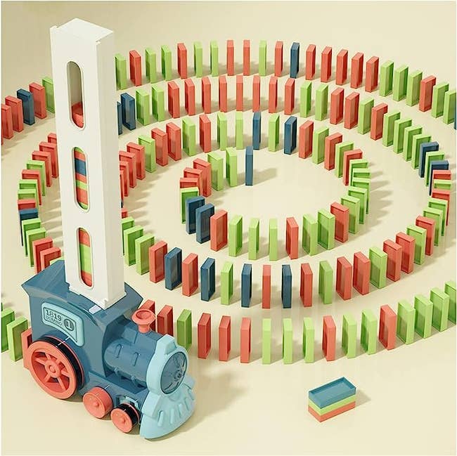 The train with a trail of spiraled dominoes placed on their end behind it