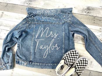 a denim jacket with pearl accents on top and a custom name written in white script on the back