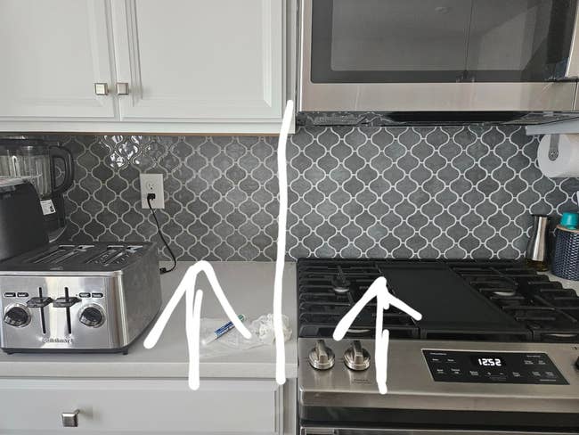 Modern kitchen with stainless steel appliances, featuring a digital microwave, toaster, and gas stove on a patterned tile backsplash
