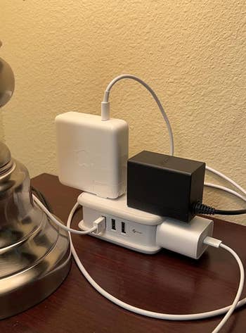 Power portion   connected  a bedside array  with respective  instrumentality  chargers and cables plugged in, adjacent  to a lamp