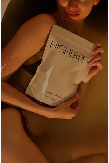 Person relaxing successful  a bath holding a pouch labeled 
