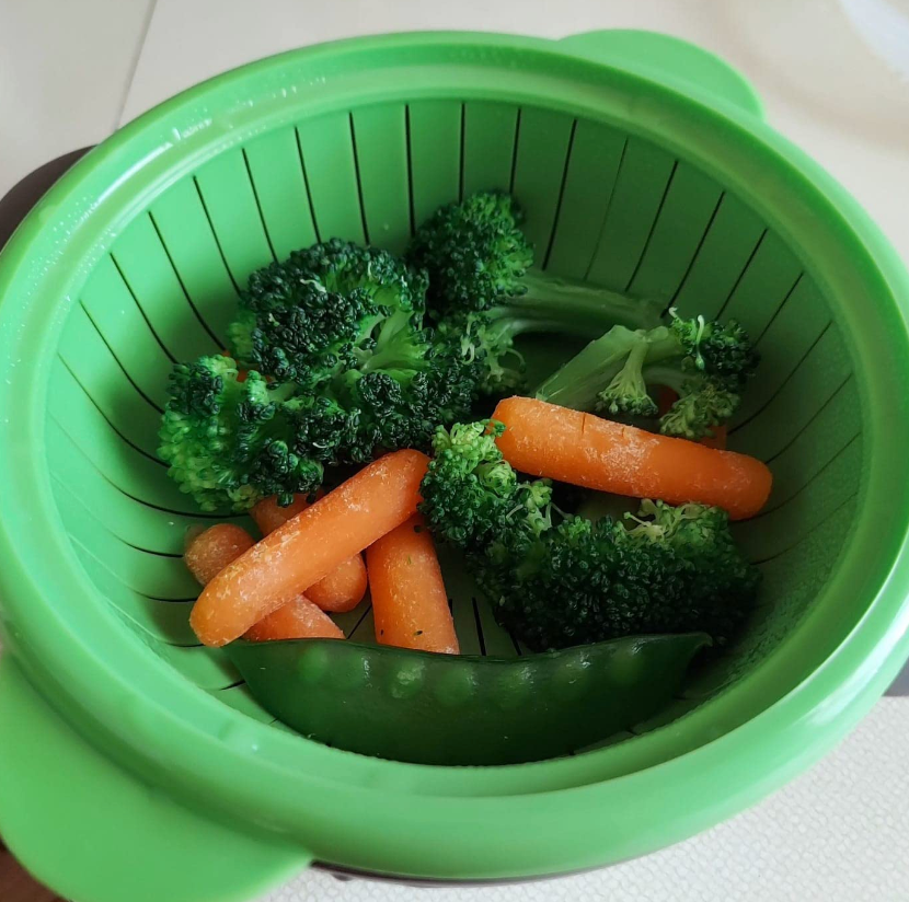 steamer with broccoli, carrots, and snow peas in it
