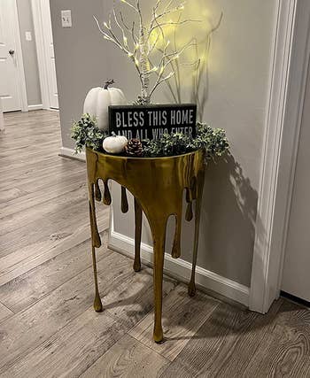 reviewer image of the gold aluminum drip table in an entryway