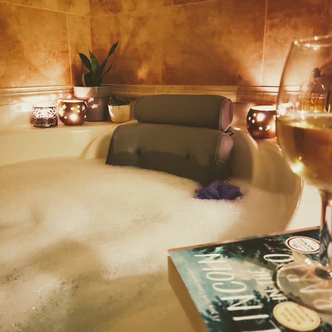 reviewer's luxurious bubble bath with bath pillow in it