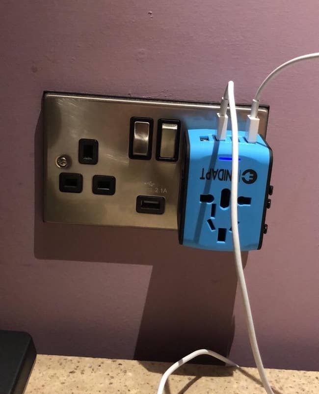 the blue adapter plugged into a wall with multiple usb cords plugged into the top