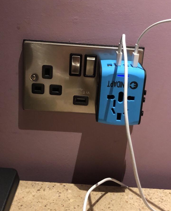 The blue adapter plugged into a wall with multiple USB cords plugged into the top