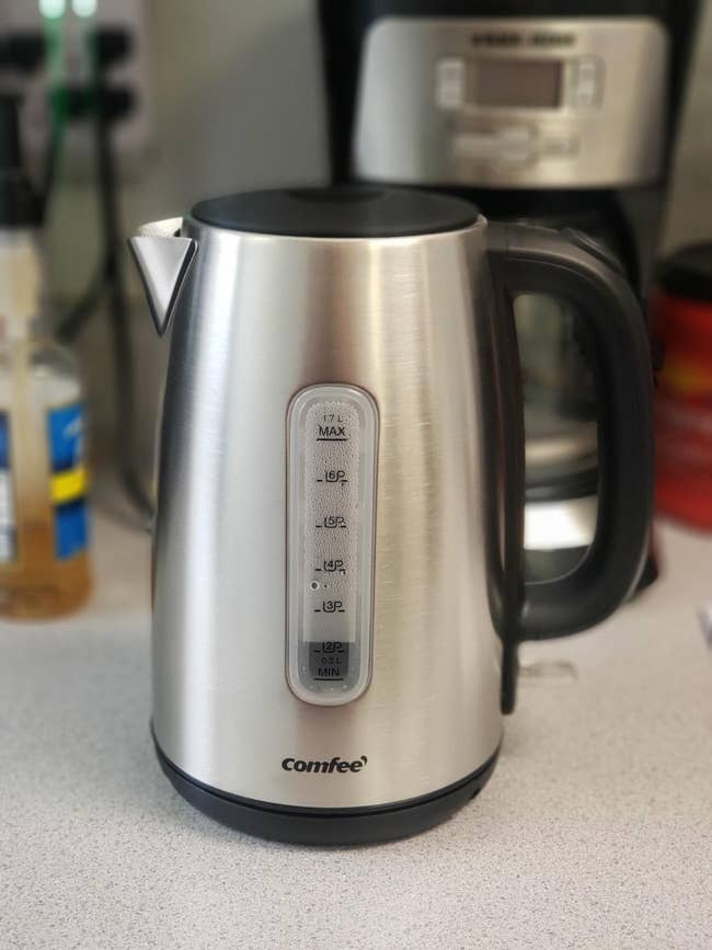 Stainless steel electric kettle by Comfee with a water level indicator on a kitchen counter