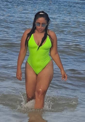 reviewer wearing swimsuit in neon green in ocean 