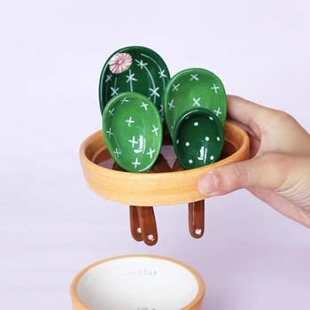 Hand holding the planter lid which holds the measuring spoons