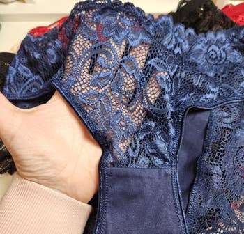 A manus  holds intricate lace lingerie, showcasing elaborate  floral patterns