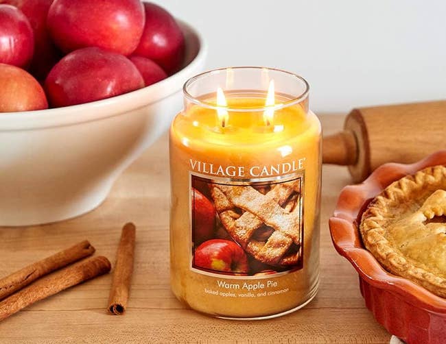 the warm apple pie candle lit next to cinnamon sticks, and a pie