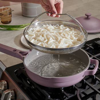 model lifting the steam basket out of the lilac pan on a stove