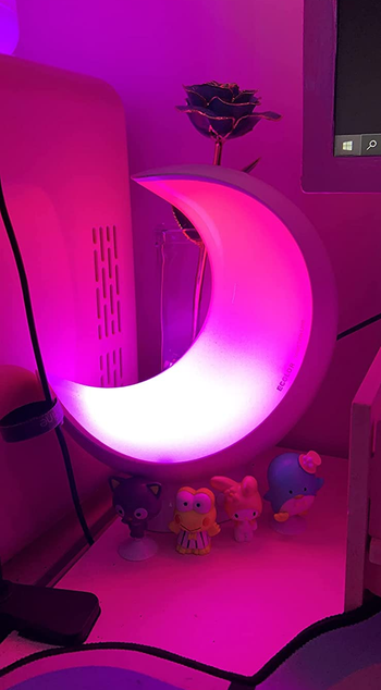 a pink glowing moon lamp in a dark room