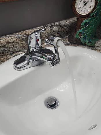 reviewer photo of the faucet extender in an upright position on a bathroom sink