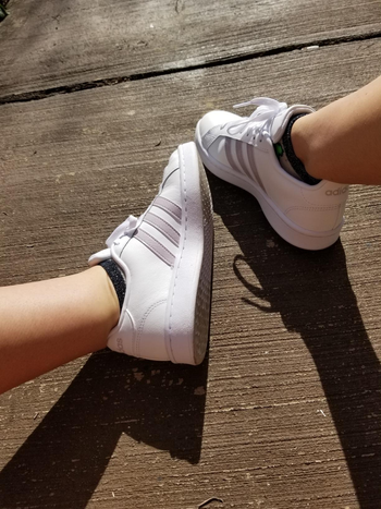 Reviewer photo of the white sneakers with three taupe stripes on the sides