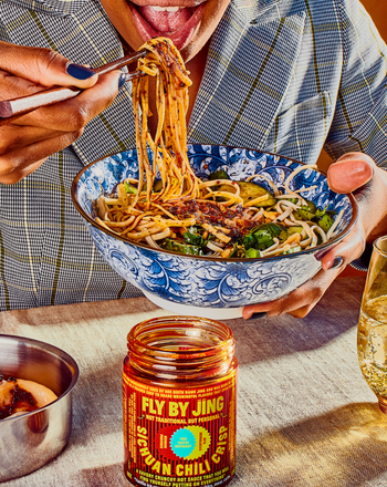 person eating noodles with the sauce in it