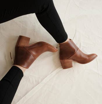 a model wearing the same heeled booties in brown 