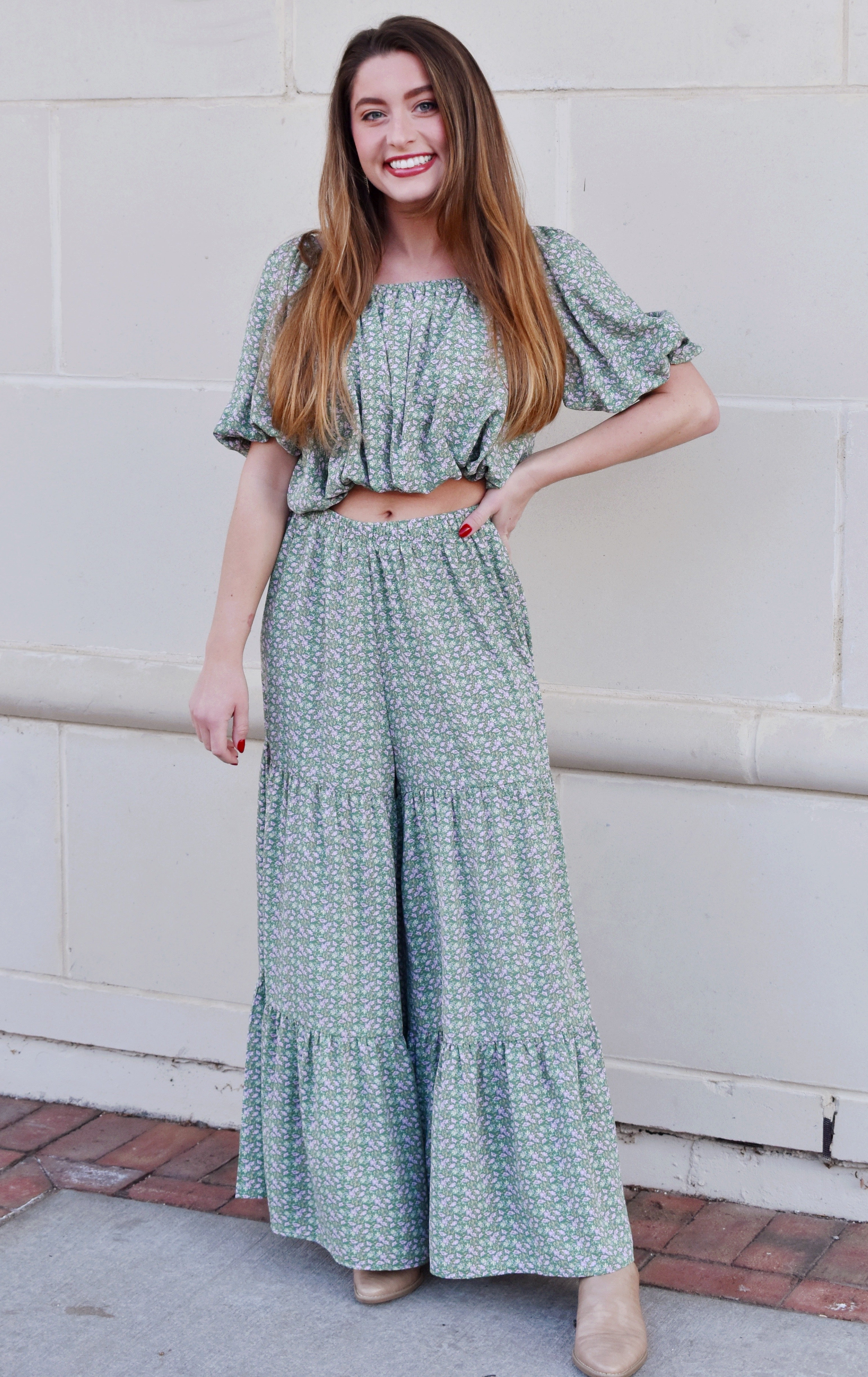 a model wearing a green short sleeve crop top gathered at the waist with matching, tiered wide-leg pants 