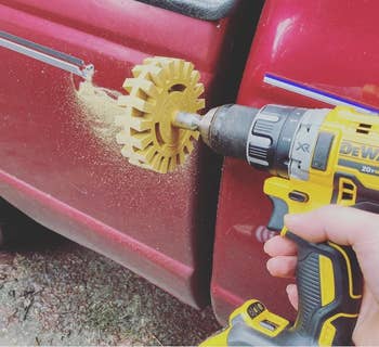 The rubber drill attachment on a drill next to a car with adhesive getting taken off