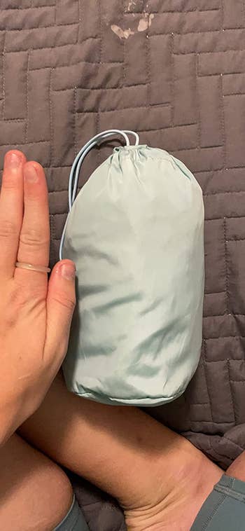 A reviewer using their hand as a reference to show the size of the pouch