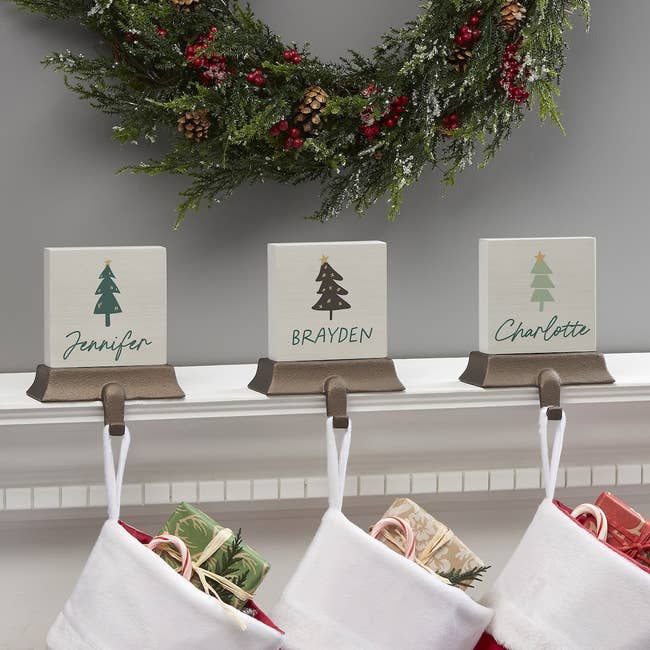 three wooden blocks with hooks attached, each has a tree and a name on it