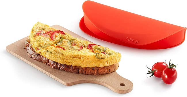 The omelet maker next to an omelet on a serving board
