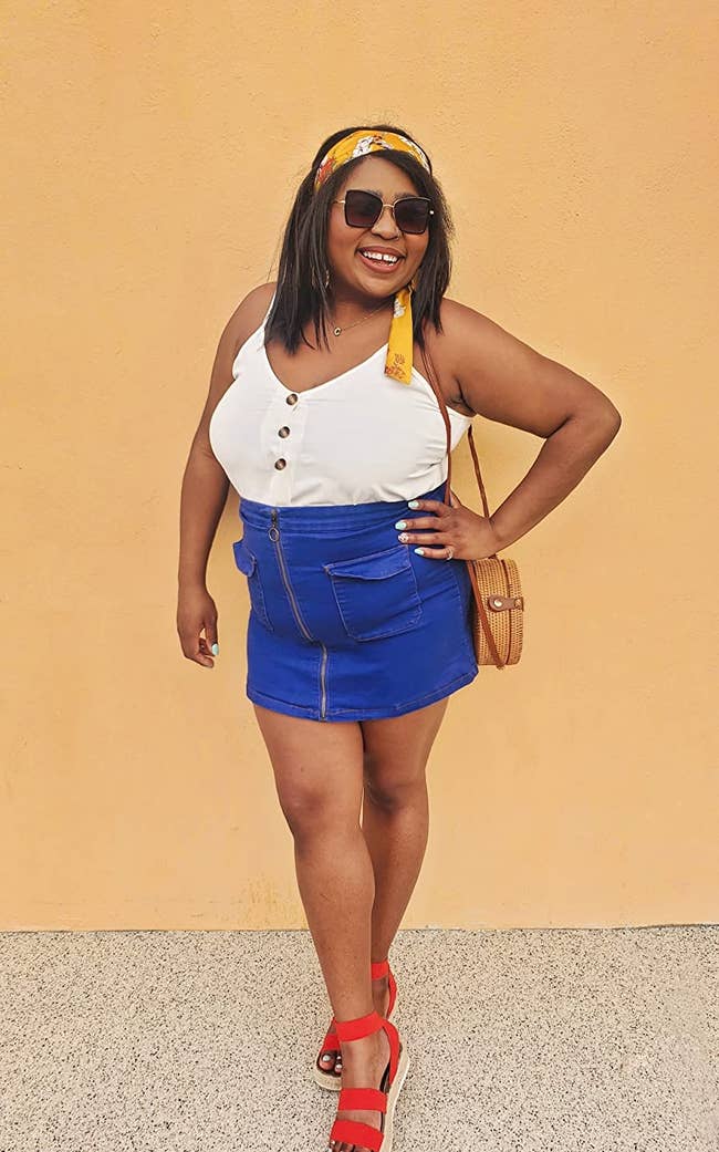 a reviewer wearing the top with a denim mini skirt