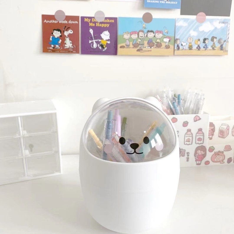 white container with clear cover with bear face holding pens