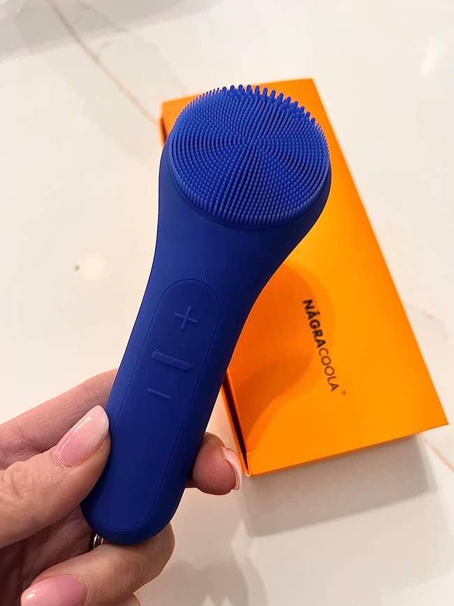 The reviewer holding the cleansing brush in their hands.