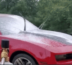 Reviewer using foam spray on red car