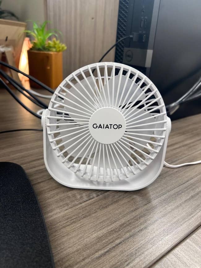 Compact GAIA TOP branded desk fan on a wooden surface next to a computer setup