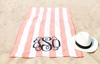 Image of peach and white towel with monogram on beach