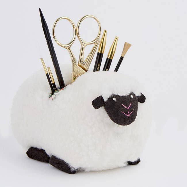 Plush sheep-shaped organizer filled with scissors and knitting accessories
