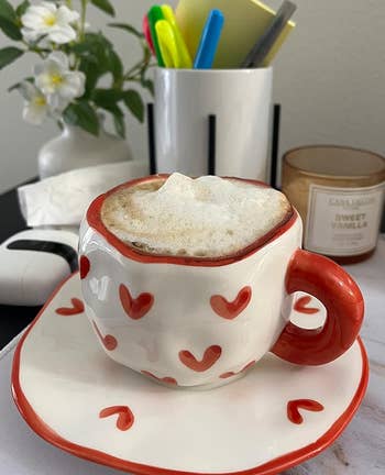 a reviewer photo of the mug and saucer set in white with little hearts allover 