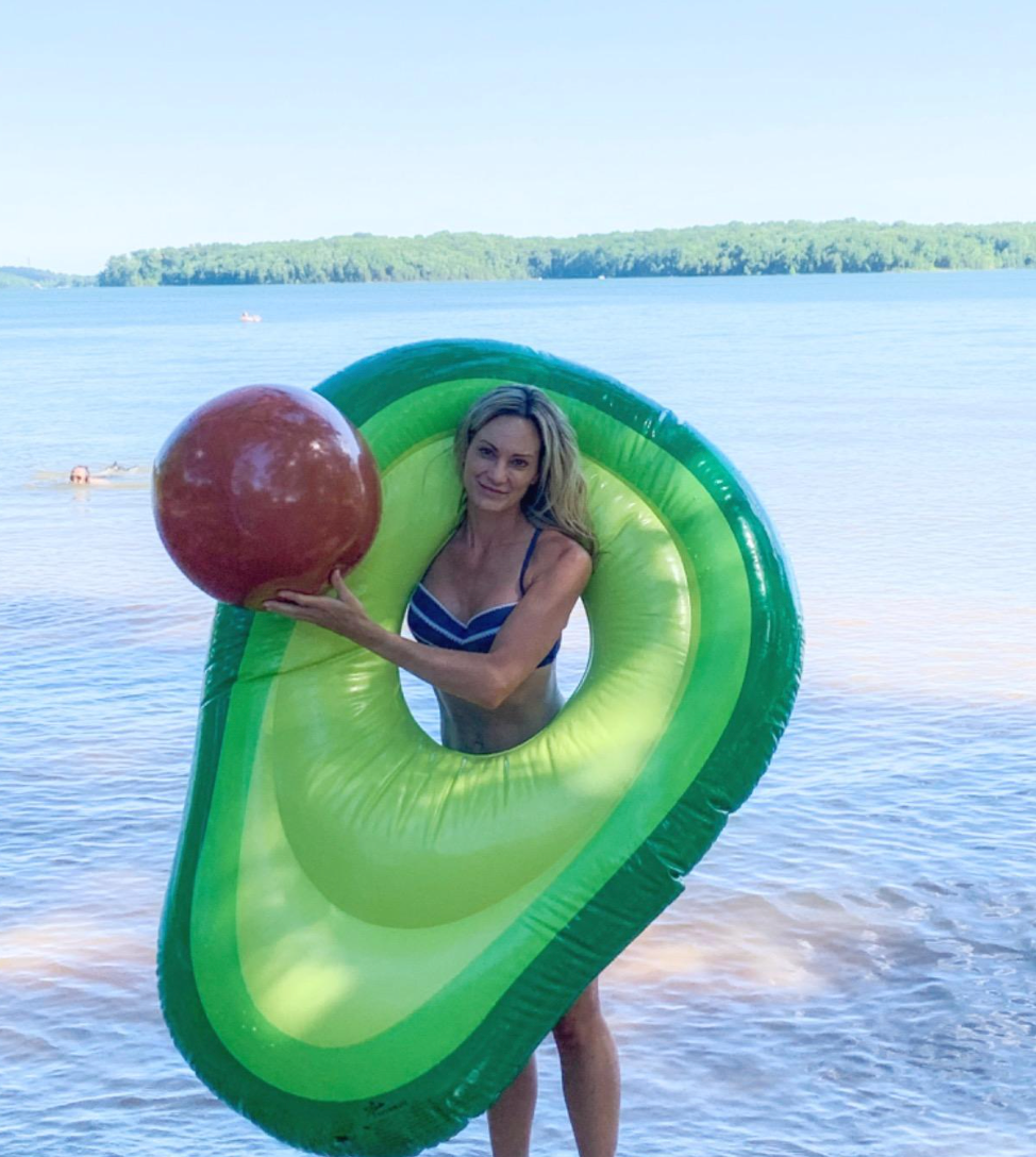 Reviewer holding avocado pool float with hole and a brown ball that's meant to be the pit