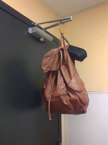 reviewer pic of a bag hanging from hinge on public bathroom door 