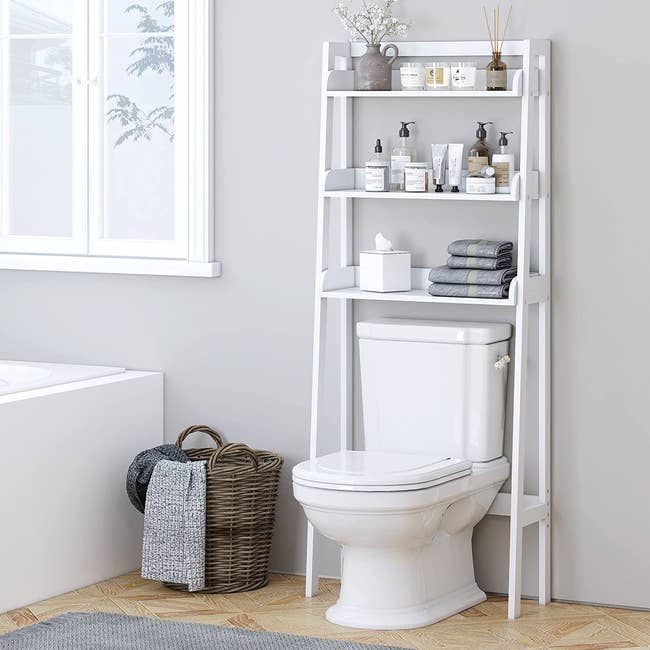 Over-the-toilet bathroom shelving unit with various items placed on shelves