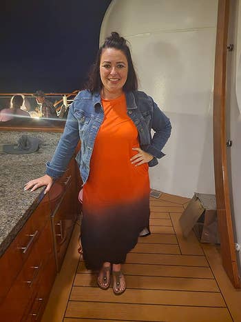 A reviewer wearing the dress in orange with a denim jacket 