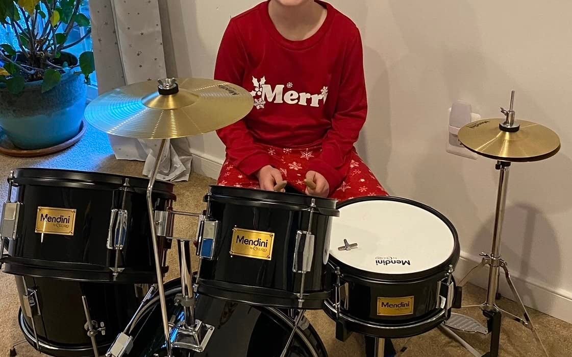 a reviewer's kid sitting at the black drum set