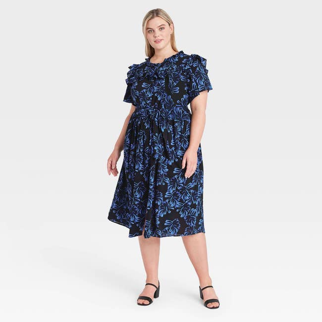 model wearing the black short sleeve dress with blue floral print