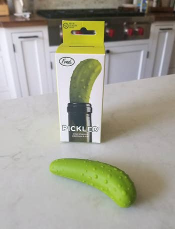 Pickle shaped wine stopper next to the box it comes in 