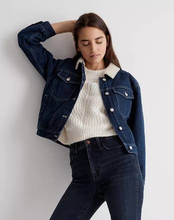 close-up of a model wearing the denim jacket with a white sweater and jeans
