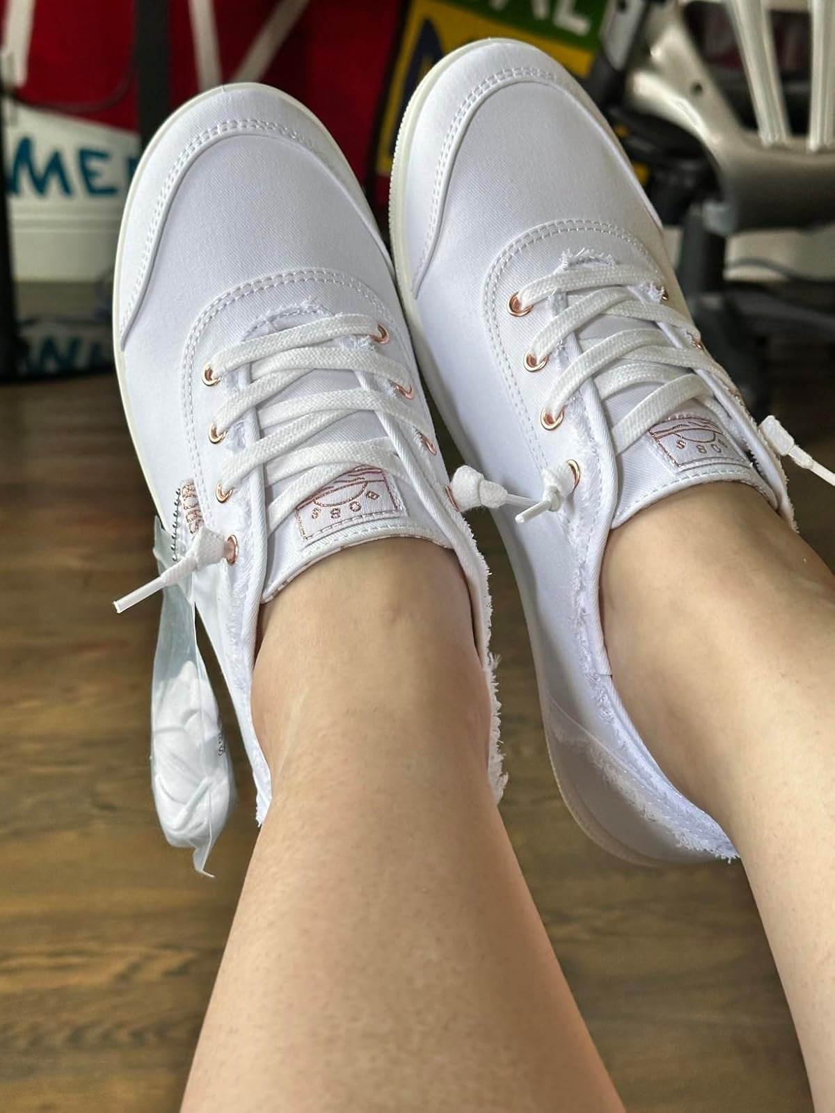 Close-up of a reviewer's feet modeling achromatic  lace-up sneakers with roseate  golden  eyelets