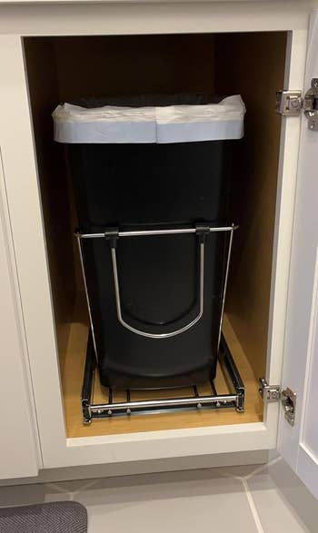 reviewer's black trash can pushed in under the cabinet